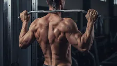 Muž při posilování zad v posilovně, stahování kladky, vypracovaná záda, fitness cvičení