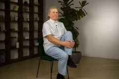 Starší žena sedí na židli, drží koleno, cvičení na protažení a rehabilitaci kloubů.